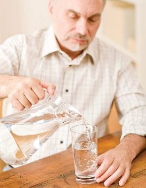 older man pouring water from pitcher